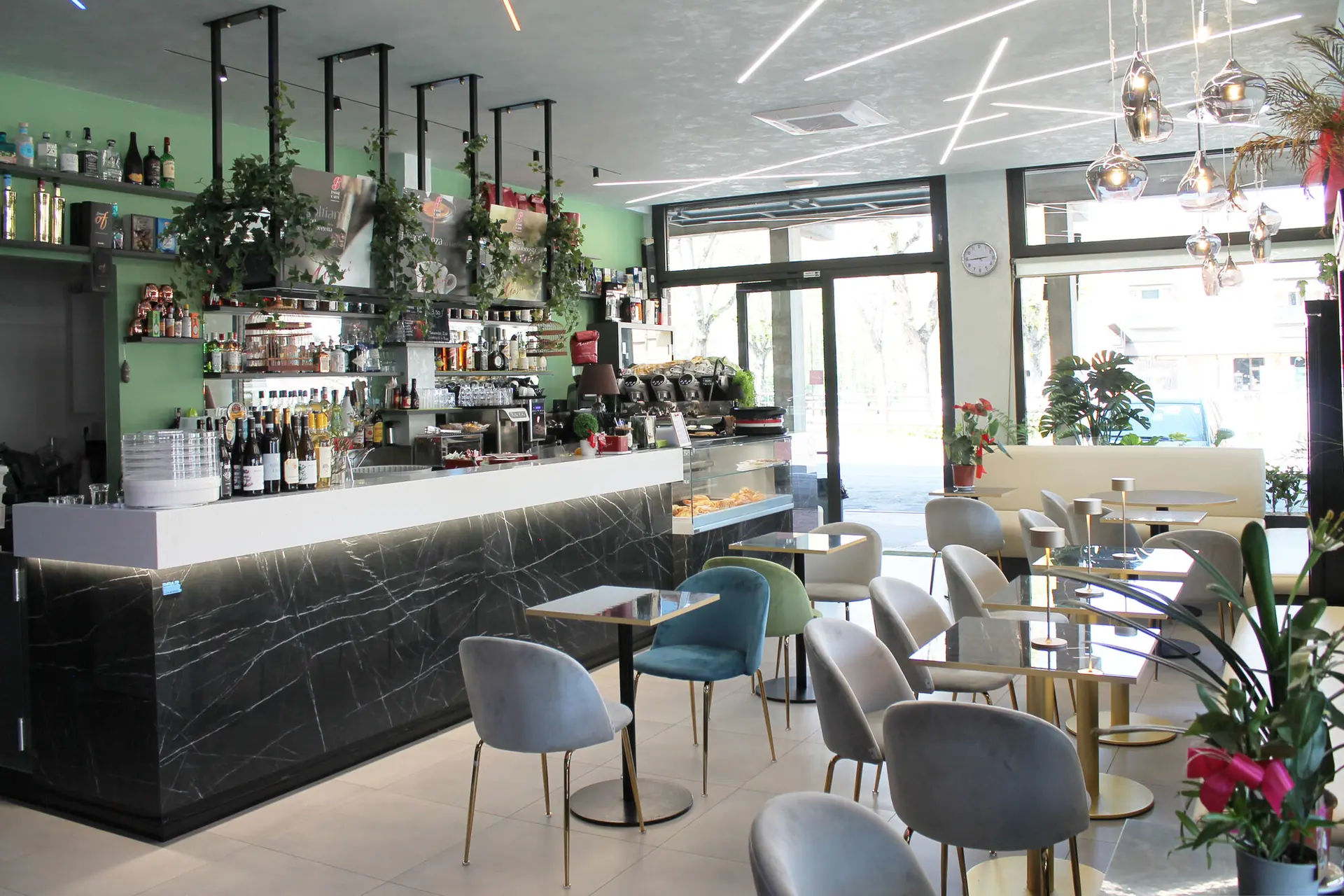 La sala di Gixy: il bancone in marmo nero, i tavolini e le vetrate sulla piazza