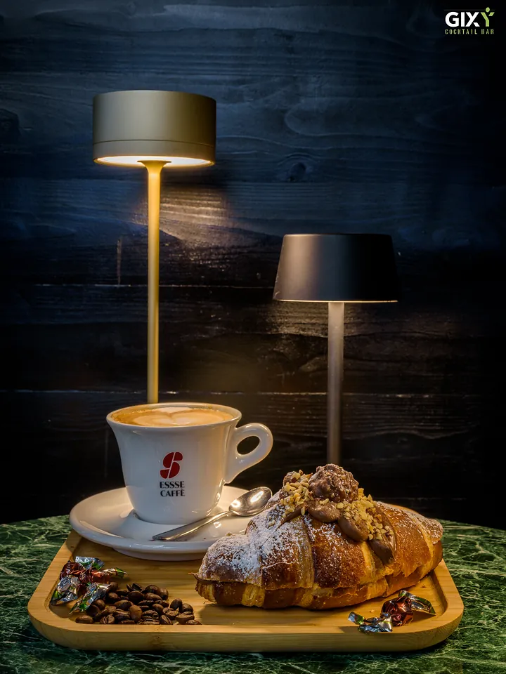 Cappuccino in tazza Essse Caffè e cornetto su un vassoio di legno
