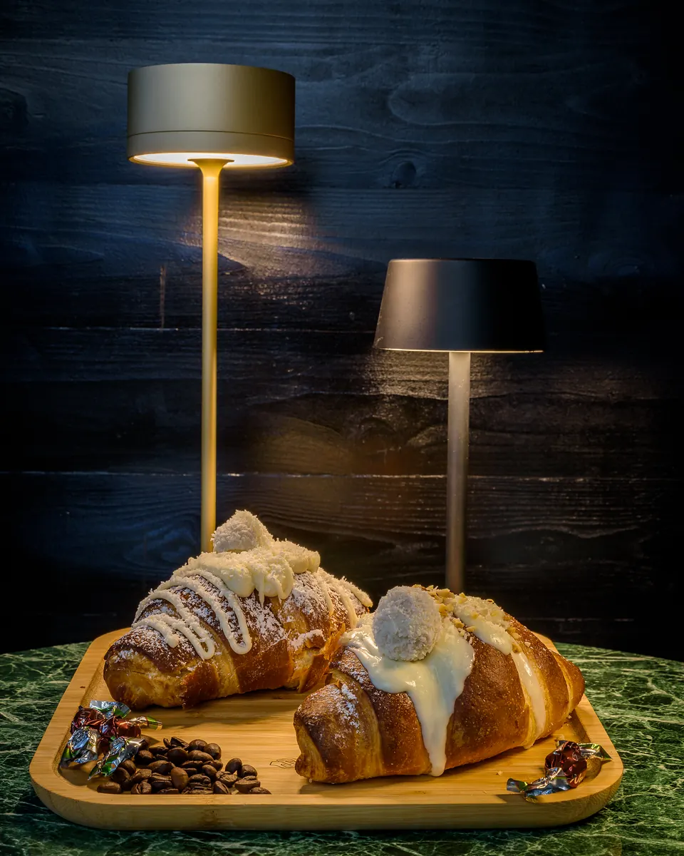 Due cornetti farciti con crema bianca su un vassoio di legno